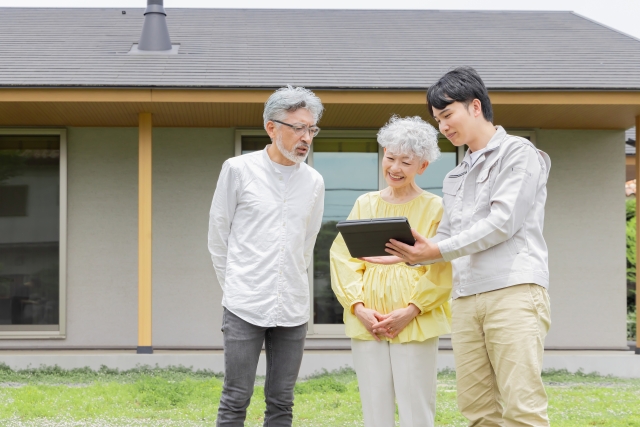 住宅の前で説明する男性とシニア夫婦